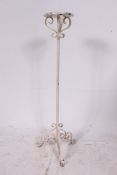 A 20th century rococo cast iron white painted shabby chic torchere plant stand having terraced top.