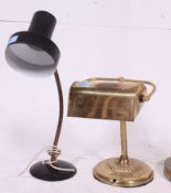 A brass bankers lamp together with a black desk top anglepoise lamp along with a floorstanding