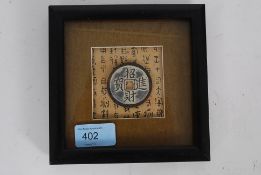 A bronze Chinese oriental good luck amulet / token, framed on inscribed paper backing.