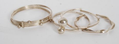 A collection of silver bangles to include puzzle bangle,  ball finial bangle and 2 others,
