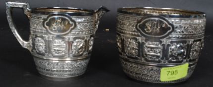 A matching silver metal creamer and sugar bowl,