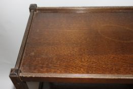 A vintage 1930's oak twin tier trolley having castors to the base with gallery sided tiers.