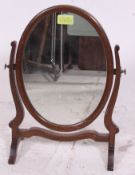 An Edwardian small mahogany toilet swing mirror having mirror on shaped arms and base beneath
