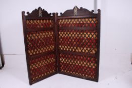 A large Victorian twin section chenille upholstered dressing screen adorned with fret pierced gilt