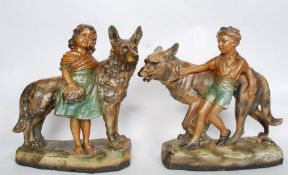 A pair of 20th century large gilt plaster Alsatian and child figure groups raised on plaster bases
