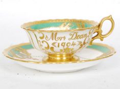 An Edwardian Minton china teacup and matching saucer. The teacup decorated with 'Mrs Dean, 1904'.