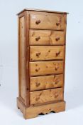 A 20th century antique style tall pedestal chest of drawers having a flared top, raised on bun feet,