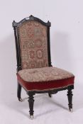 A Victorian ebonised mahogany aesthetic movement nursing chair.