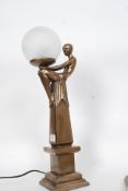 An Art Deco style bronze effect lamp with globe shade to top on a square plinth base.
