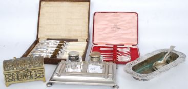 A collection of silver plated wares to include a desk tidy with glass inkwells, boxed flatware,