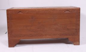A 1950's camphor trunk of Chinese origin with hinged top and carved decoration having open storage
