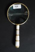 A vintage style hand held brass and mother of pearl handled magnifying glass.