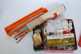 A vintage biscuit tin containing buttons and sewing accessories along with several pairs of