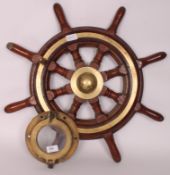 A brass vintage ships porthole window together with a brass and teaks ships wheel with number 8340
