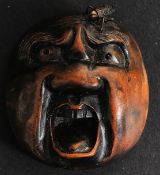 A 20th century Japanese wooden bhudda face type netsuke having unusual applied bronze fly atop (