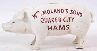 A cast iron advertising piggy bank money box in the form of a pig with notation to side.