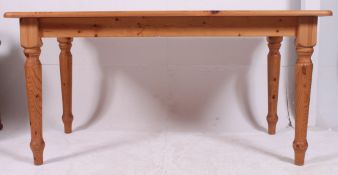 A contemporary country style pine kitchen / dining table raised on turned legs with a flared top