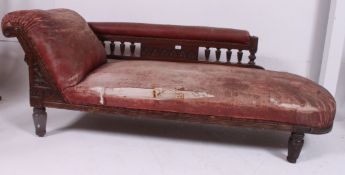 A Victorian oak and faux leather chaise longue sofa day bed raised on turned legs with spindle back