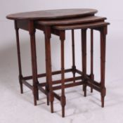 An early 20th century mahogany and walnut graduating trio nest of tables being raised on faux