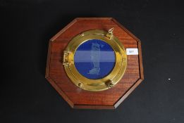 A  vintage style brass porthole mirror mounted to a mahogany plaque