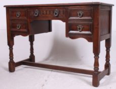 A Jaycee Jacobean revival carved oak writing table desk raised on block and turned legs united by
