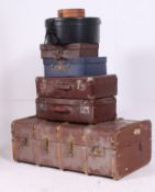 A stack of vintage trunks to include a canvas and wooden bound steamer trunk, retro suitcases.