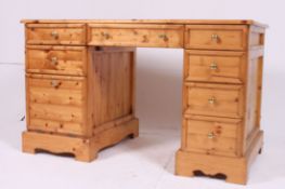 A 20th century antique style pine twin pedestal desk having drawers to each pedestal having flared
