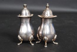 A pair of silver hallmarked cruets, each piece with cusped rim and raised on four outswept feet.