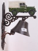 A 20th century cast iron wall hanging bell and bracket, decorated to the top with a Land Rover.