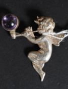 A silver hallmarked broach of a Cherub playing a pipe blowing a bubble set with an amethyst stone 8.