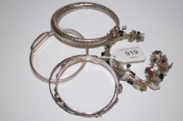 5 silver and white metal bangles some set with gem stones.