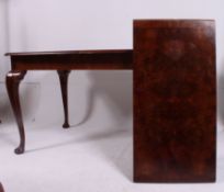 A 1950's walnut dining table raised on cabriole legs with a burr walnut inlaid extending table top