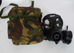 A 20th century military black rubber gas mask, within a camouflage cloth case.