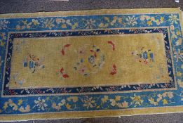 A 20th century Chinese rug having geometric patterns to the blue borders with central yellow ground