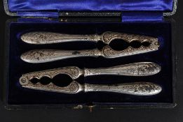 A Victorian cased set of silver plated cast iron nut crackers having chased decoration with shaped