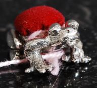 A 20th century white metal (stamped 925 for silver ) frog shaped pin cushion having red baised pin