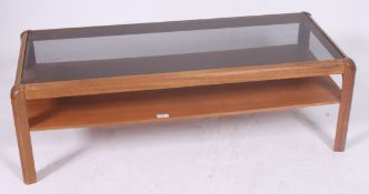 A 1970's smoked glass and teak rectangular coffee table having inset glass top raised on end