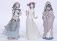 2 Nao by Lladro figurines to include Fashion Girl and Girl Standing holding rabbit in both hands.