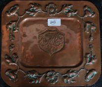 A 19th century Arts & Crafts copper plaque being hammered into relief bearing central monogram