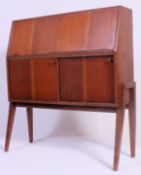 A vintage 1950's retro bureau being raised on angled supports with fall front bureau atop.