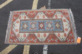 An Islamic wood rug with pale blue ground having shaped central diamond lozenge design and a