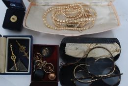 A faux pearl necklace, faux tortoiseshell glasses, enamel badges and other items.