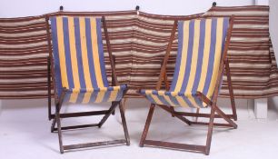 A pair of vintage mid century folding deck chairs along with a similar aged stripped wind breaker