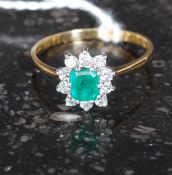 An 18t gold emerand and diamond ladies dress ring having cushion cut emerald with surrounding
