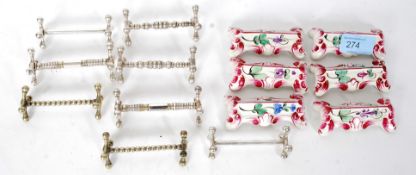 A collection of silver plate knife rests along with a set of ceramic knife rests