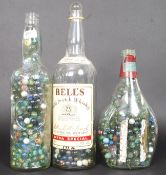 A collection of 3 oversized whisky bottles containing a variety of marbles,