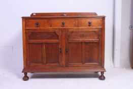 A 1930's golden oak sideboard dresser being raised on bell feet having  2 short drawers over