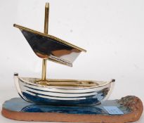 A polished steel / chrome decorative rowing boat ship displayed on a glazed sea affect tile marked