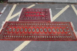 Two 20th century Indian style woven rugs (one a runner) both on red ground with tassled ends.