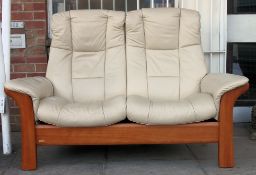 An Ekornes Stressless reclining soft cream leather two seater settee with mahogany show wood frame.